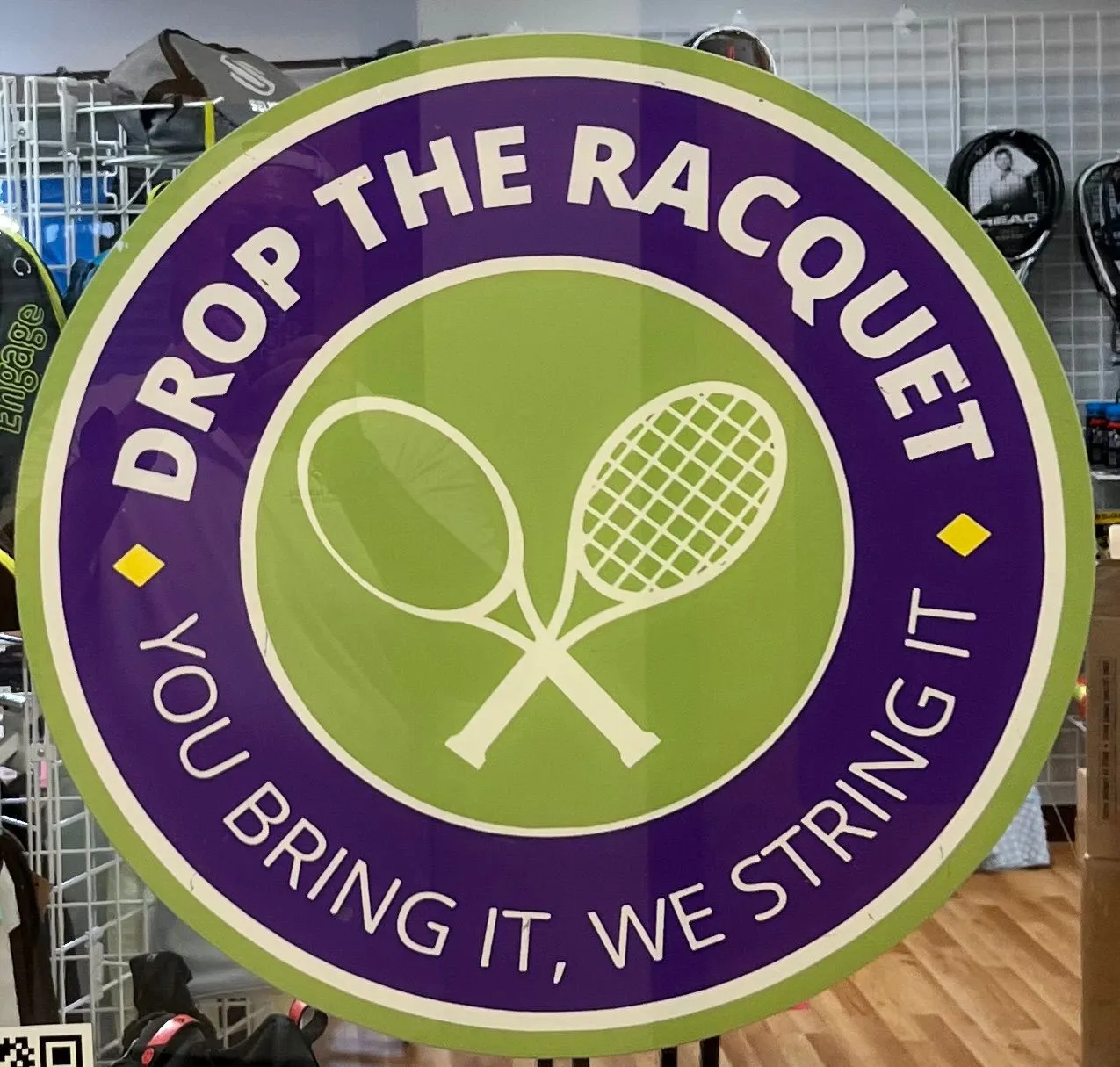 Drop the Racquet logo with crossed racquets inside a green and purple circle